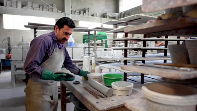 Male artisan removing a ceramic bowl from the mold at a pottery workshop