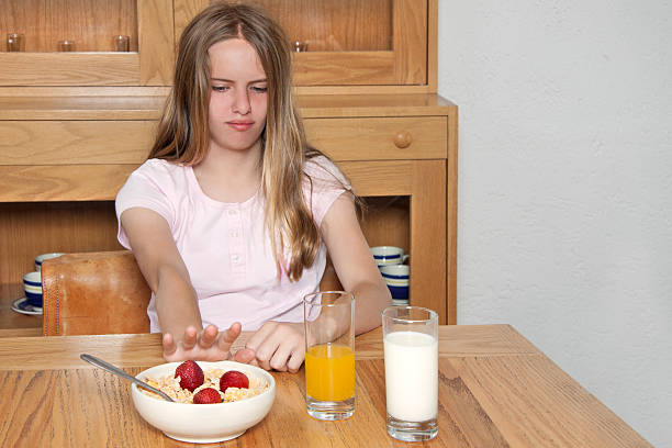 rejecting food young teenager sitting in a dining room rejecting food with a disgusting face eating disorder stock pictures, royalty-free photos & images