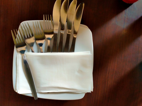 Forks and cutlery wrapped in tissue are on the table