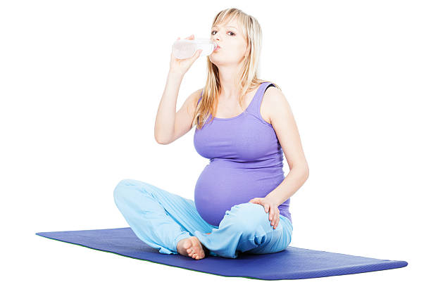 istock Pregnant young woman drinking water on exercise mat isolated 175448486