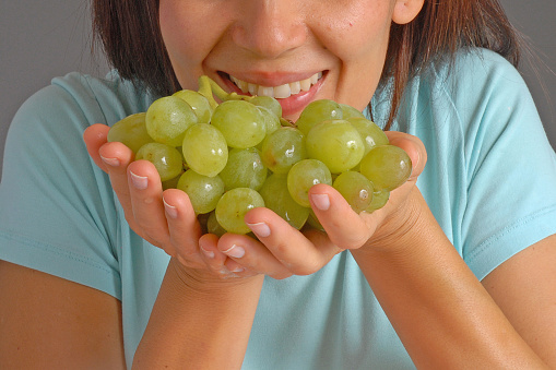Happy woman holding green grapes fruit bunch portrait.