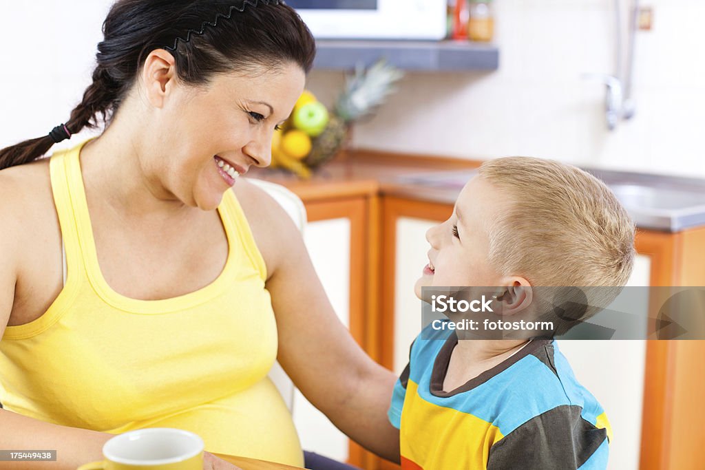 Femme enceinte et son enfant parler dans la cuisine - Photo de Abdomen libre de droits