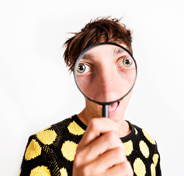 istock Young man's eyes are hugely enlarged by magnifying glass 175450231