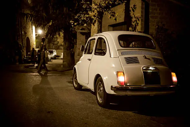 Vintage Fiat 500 parked on street of Montepulciano old town (Tuscany, Italy). Grain and vignette added.