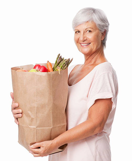 senior donna tenendo il sacchetto di generi alimentari freschi isolati - senior adult aging process supermarket shopping foto e immagini stock