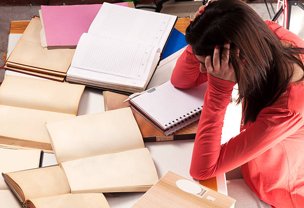 Examination stress Female student seems thoughtfully with many open books and notebooks on the desk face down stock pictures, royalty-free photos & images