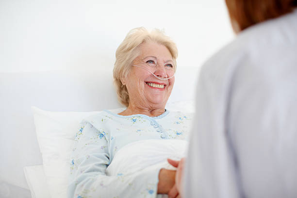 Her positive outlook helps with the healing - Senior Care An elderly female woman receives a comforting visit from her doctor after an operation - Copyspace tracheotomy tubing stock pictures, royalty-free photos & images