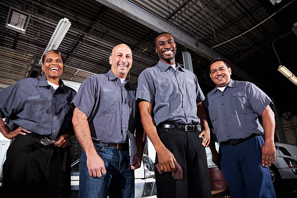 Multi-ethnic workers at trucking facility Multi-ehnic workers in service garage at trucking company. repairperson occupation stock pictures, royalty-free photos & images