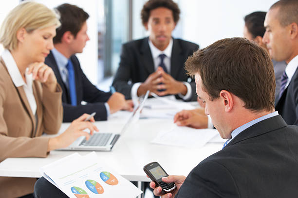istock Businessman Checking Phone During Meeting In Office 175453559
