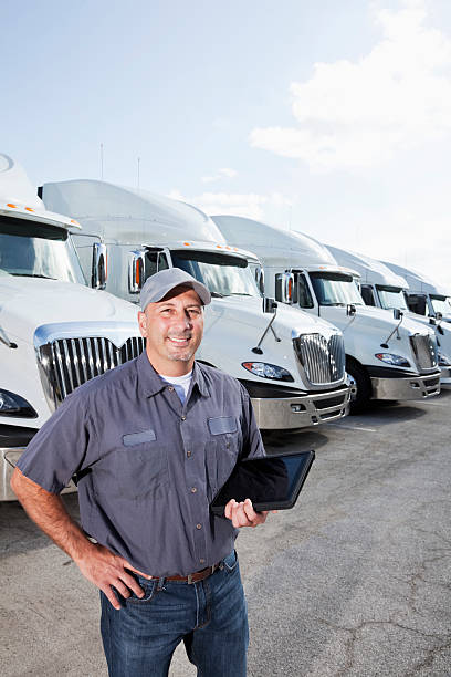 istock Truck driver in front of big rigs with digital tablet 175453911