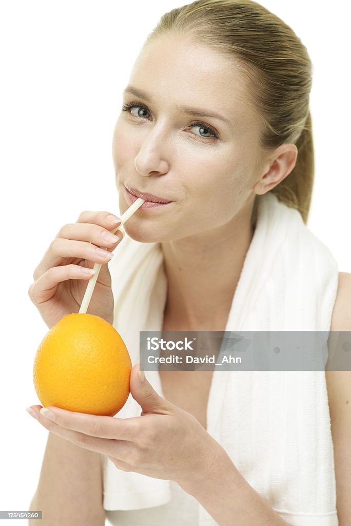 Giovane donna godendo arancione con una cannuccia dopo l'esercizio fisico - Foto stock royalty-free di Adulto