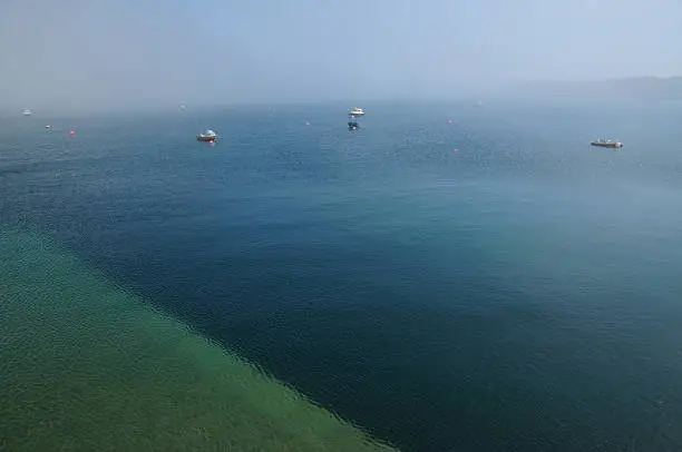 Wide angle image of approaching fog at small harbor with slipway in shallow clear water.