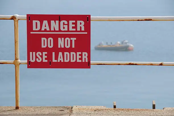 Telephoto image of warning sign and small harbour in Summer sea fog.