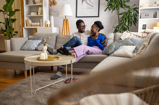 Two people, young black couple sitting on sofa at home.