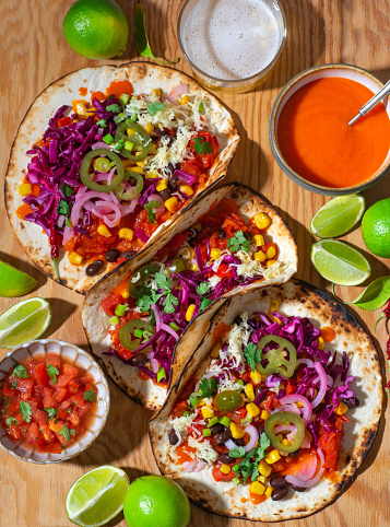 Mexican tradition recipes:  testy vegan Tacos, plant based diet,  with black beans, corn, jalapeno peppers, red cabbage, salsa, coriander leaves and marinated onion. Top view