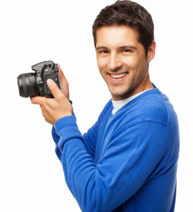Portrait of a happy young man in blue t-shirt holding DSLR camera. Horizontal shot. Isolated on white.