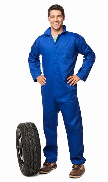 Full length portrait of an automotive technician with a spare tyre. Vertical shot. Isolated on white.