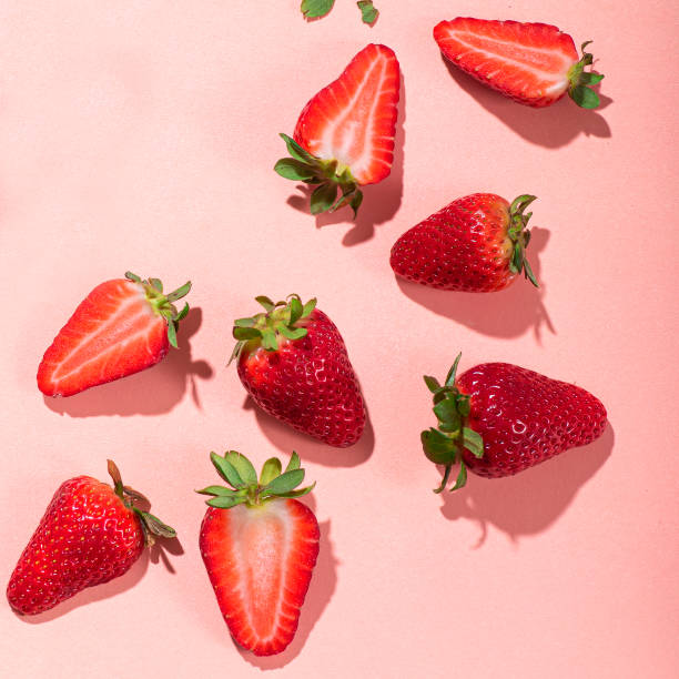 istock Fresh strawberries cut into slices on a pink background. Square crop, sunshine and shadows 1754552530