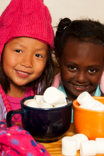 Adorable little girls warming up with hot chocolate and marshmallows