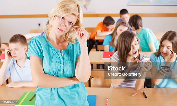 Frustrated Teacher In Classroom Pupils Behind Her Are Not Listening Stock Photo - Download Image Now