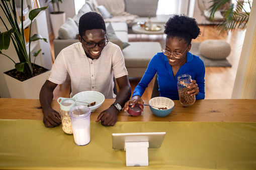 Two people, young black couple having breakfast while sitting at the table at home.