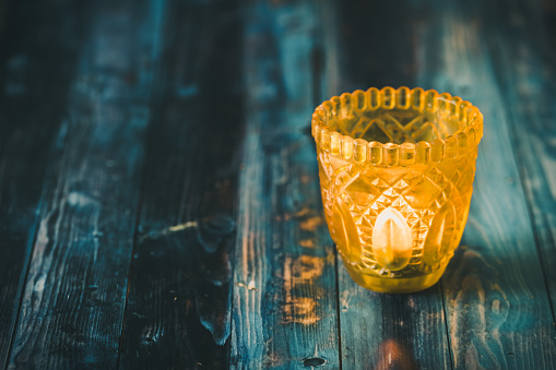 Yellow glass with tea light on blue wooden table