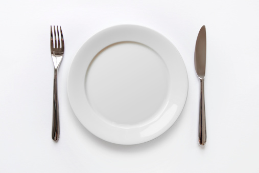 Plain white plate with fork and knife on white background