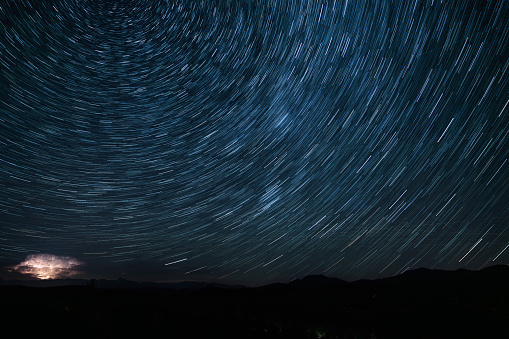 Wide panoramic view, created from multiple images, showing earth’s rotation and a beautiful startrail from the Slovenian wild highlands, during a summer night in august