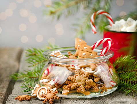 ginger cookies in a jar, sweets, a mug of cocoa and fir branches on a wooden table