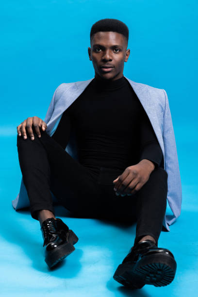 istock Attractive handsome young African man sitting over blue background in studio isolated serious concentred model man posing for clothes store shop 1754619661