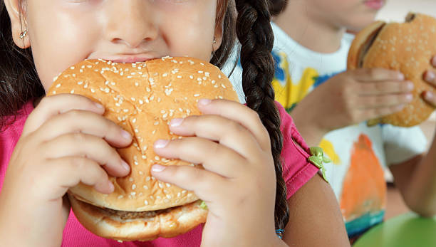 chłopiec i dziewczynka z hamburgerów - overweight child eating hamburger zdjęcia i obrazy z banku zdjęć