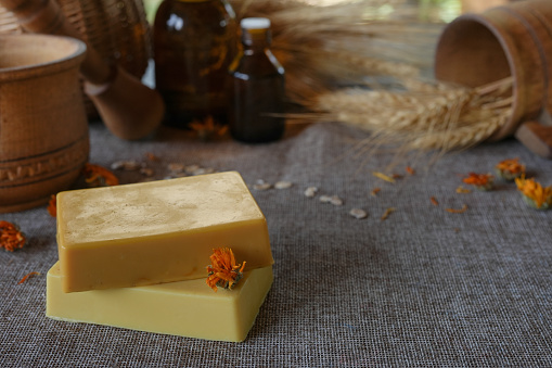 Natural handmade soap with dry calendula (pot marigold) on rustic wooden background. Natural soap bars with essential oils and medicinal plants extracts. Side view,copy space for text, product place.