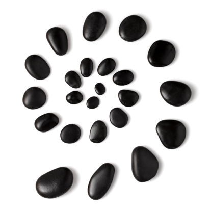 A spiral of black massage stones on white background