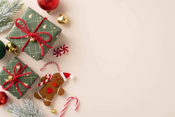 istock Holiday magic comes to life creatively, presenting green gift boxes, baubles, gingerbread man ornament, jingle bells, candy cane, frosty fir branches from a top view on a light backdrop with ad space 1754682867