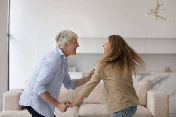Joyful excited adult and senior father training energetic social dance Joyful excited adult child and active senior father training energetic social dance at home together, having fun, enjoying family leisure time, active hobby, laughing, moving teacher retirement party stock pictures, royalty-free photos & images
