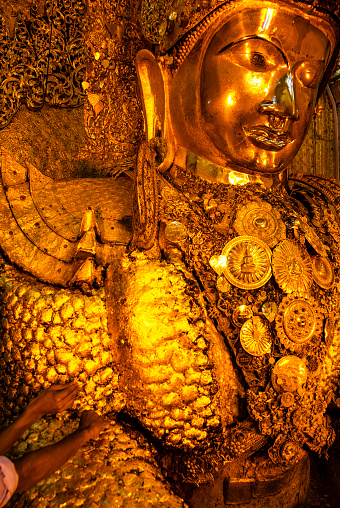 People stick gold leafs on the golden Mahamuni Buddha statue, Mahamuni Paya pagoda, Mandalay, Myanmar, Asia