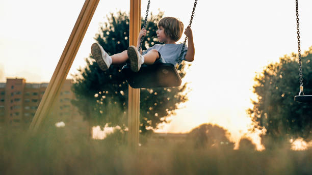a child plays with the swing on the playground stock photo