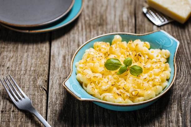 istock Mac and cheese in baking dish with basil on top and grated cheese in background placed on a wooden rustic board 1754706343