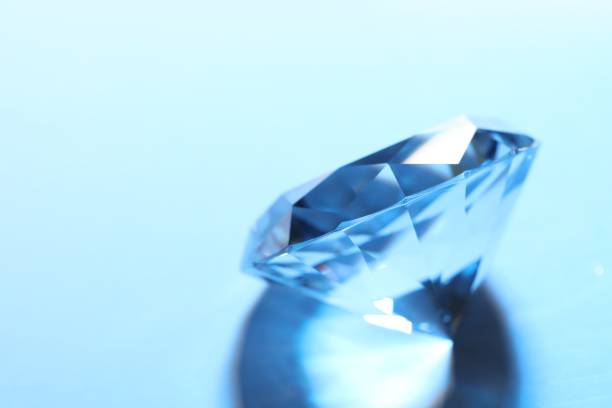 istock Beautiful dazzling diamond on blue background, closeup. Space for text 1754716519