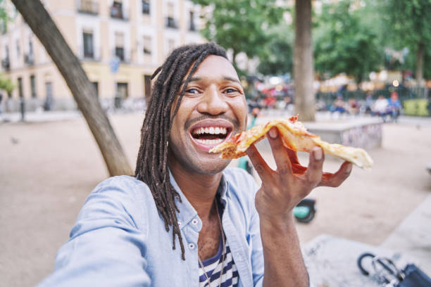 istock Excited man making selfie while eating pizza. Laughing man with dreadlocks having fun during dinner. 1754741795