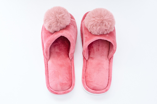 Pink home fluffy slippers on white background. Comfort and warmth accessories