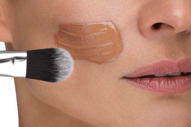 istock Woman applying foundation on face with brush, closeup 1754745943