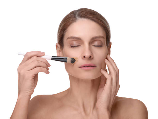 istock Woman applying foundation on face with brush against white background 1754746708
