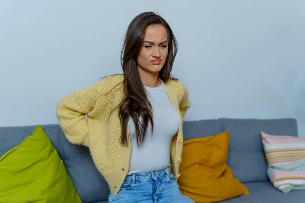 istock Young woman sits in discomfort at home, while seeking a solution for her pain 1754746726