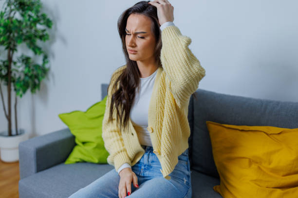 istock Frustrated young woman suffering from a headache, while sitting on the sofa at home 1754747283