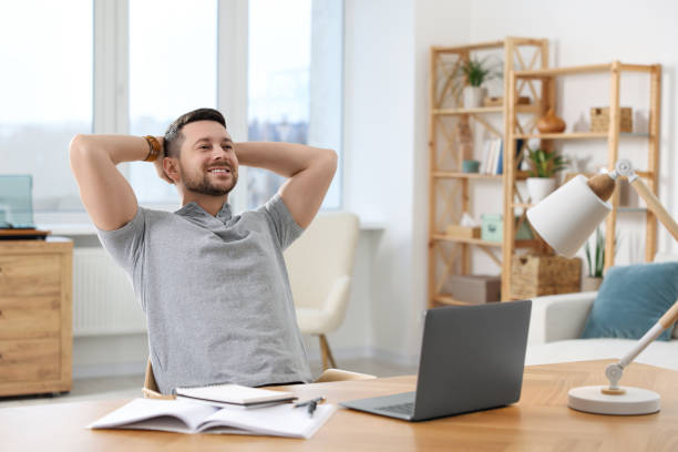 istock Happy man having break while working with laptop at wooden desk in room 1754747811
