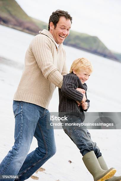 Padre E Hijo En La Playa Sonriendo Retención Foto de stock y más banco de imágenes de 30-39 años - 30-39 años, Actividad, Adulto