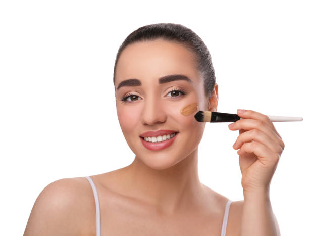 istock Woman applying foundation on face with brush against white background 1754759975