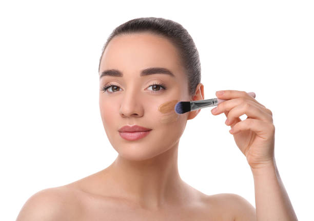 istock Woman applying foundation on face with brush against white background 1754759979