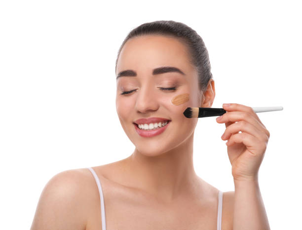 istock Woman applying foundation on face with brush against white background 1754761040
